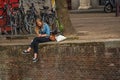 Young girl alone sitting on wall at the canalÃ¢â¬â¢s edge, eating ice cream in Amsterdam.